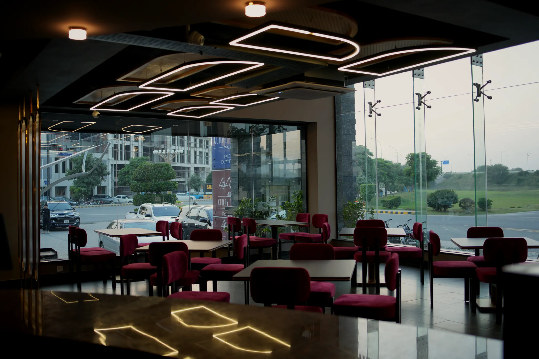 Ground-floor dining room at dusk with crimson velvet chairs